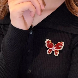 Close-up of a sparkling red butterfly brooch with crystals pinned on a black sweater