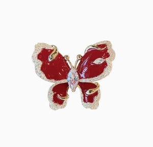 Close-up of red enamel butterfly brooch with gold plating and sparkling zircon stones