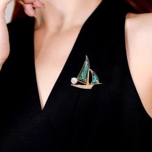 Broche voilier élégante en nacre d'abalone et perle sur un haut noir chic