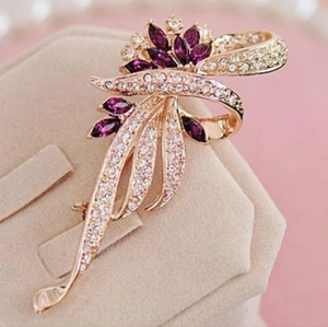 Macro shot of gold ribbon brooch with purple marquise cut gems and sparkling white diamonds