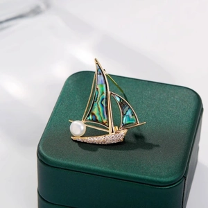 Broche voilier élégante avec voiles en opale, perle et cristaux sur coffret en cuir vert