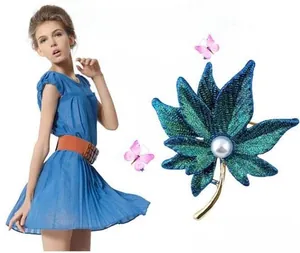 Detail of blue-green sequin maple leaf brooch with center pearl and golden stem