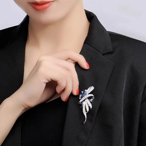 Elegant silver leaf brooch with blue pear-cut gems pinned on a black suit lapel