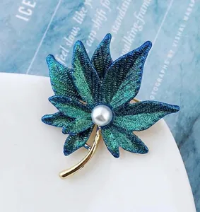 Detailed macro view of a blue gradient maple leaf brooch with a central pearl inlay