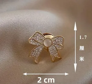 Close-up of bow brooch with rhinestone details and opal stone, size 2cm by 1.7cm