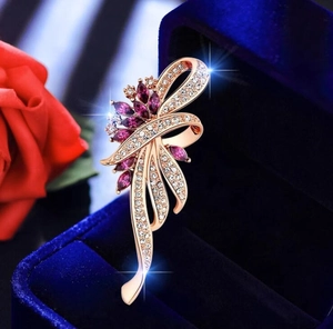 Detailed macro of rose gold floral brooch with purple marquise stones on velvet box