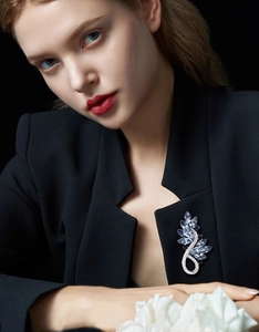 Vue détaillée d'une broche de luxe en cristaux bleus sur un blazer de costume noir