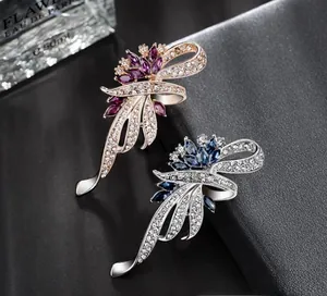 Detail of rose gold and silver ribbon brooches with maroon and blue marquise crystals