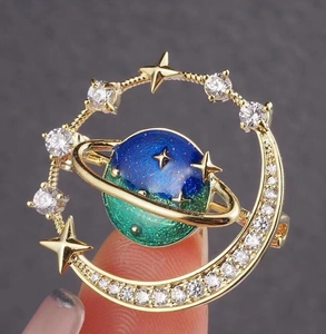 Detail of celestial planet brooch featuring moon crescent and blue enamel with zircon