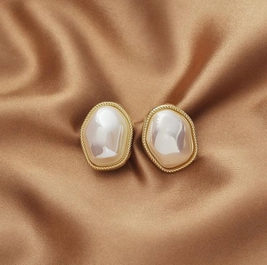 Detailed close-up of vintage irregular pearl earrings with golden twisted rope borders