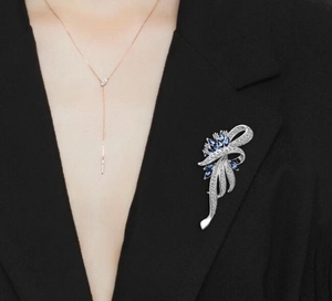 Detailed close-up of blue marquise gemstone brooch and necklace on a black blazer