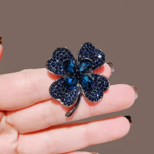 Élégante broche trèfle à quatre feuilles en cristaux bleu marine tenue à la main