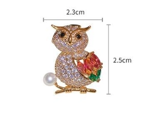 Detailed close-up of crystal owl brooch with colorful gems and a small white pearl