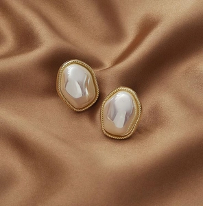 Detail of vintage irregular pearl earrings with golden twisted rope frame on silk
