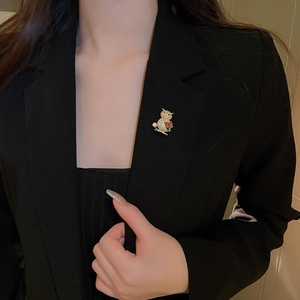 Detailed view of luxury owl brooch with crystals and pearl on a black suit lapel