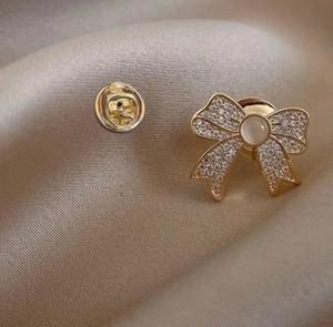 Close-up of golden bow brooch with sparkling crystals and pearl on champagne satin