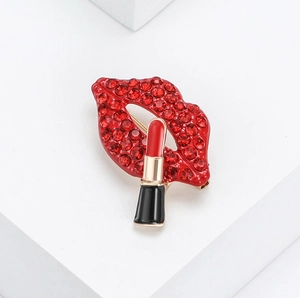 Elegante spilla labbra con strass rossi e dettaglio rossetto in miniatura su bianco