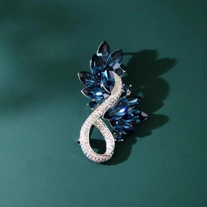 Broche luxueuse en forme de plume avec cristaux bleus et strass sur fond vert sombre