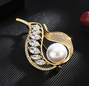 Vue macro d'une broche feuille avec perle blanche et cristaux de zircon taille marquise