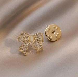 Macro detail of a bow-knot brooch featuring inlaid zircon stones and a cat-eye gem centerpiece