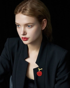 Detailed view of luxury red crystal apple brooch on a black suit jacket for women