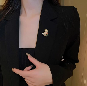 Detailed shot of an owl brooch with crystal accents on a black blazer lapel