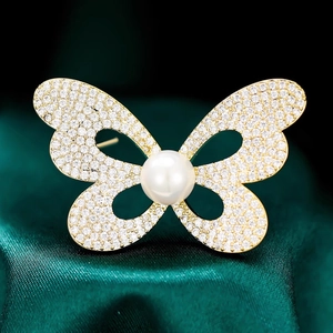 Élégante broche papillon en or avec diamants pavés et une grande perle blanche centrale