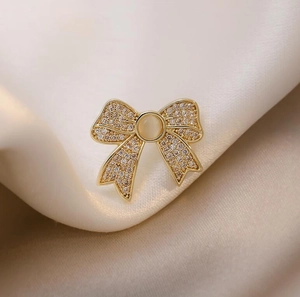 Macro shot of gold bow brooch with tiny pavé diamonds and a central cat eye gemstone