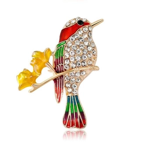 Vue macro détaillée de la broche oiseau en émail coloré avec strass brillants et base dorée
