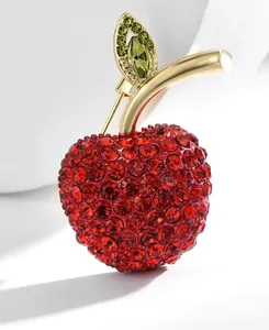 Macro shot of luxury red crystal apple brooch with green leaves and gold plating