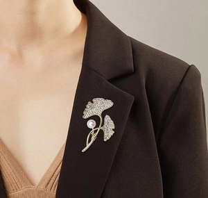 Detail of ginkgo leaf brooch with shimmering crystals and a white pearl on a blazer