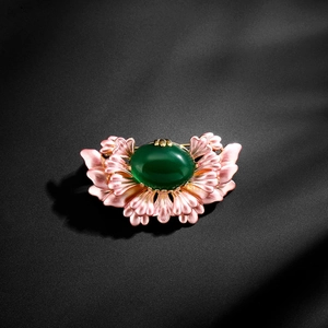 Detailed macro view of retro floral brooch with green gemstone and pink enamel petals