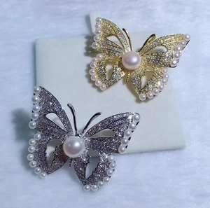 Gros plan de broches papillon avec cristaux scintillants et perles en finitions or et argent