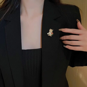 Detailed close-up of a luxury owl brooch with crystals and pearls on a black suit jacket