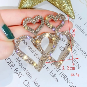 Dettaglio macro di orecchini a doppio cuore in argento con strass lucidi e design a strati