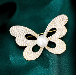 Élégante broche papillon en or avec diamants et une grande perle blanche ronde au centre