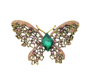 Détail d'une broche papillon dorée avec strass roses et pierre précieuse verte