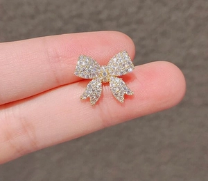 Macro detail of a sparkling bow brooch featuring pave-set rhinestones in a gold plating