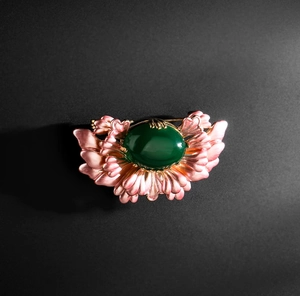 Detailed macro view of vintage luxury begonia flower brooch with large green oval gemstone