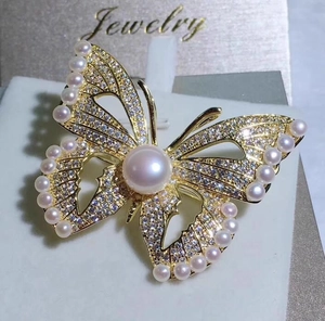 Vue macro d'une broche papillon dorée avec perles et zircons sur une carte à bijoux