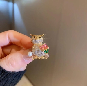 Detail of owl brooch with gold plating, sparkling zircons, gemstones, and a white pearl