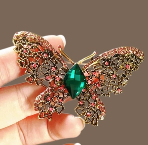 Vue détaillée d'une broche papillon vintage avec pierre verte et strass roses