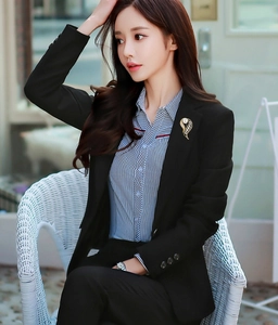 Détail d'une broche feuille dorée avec perle blanche sur un blazer noir professionnel