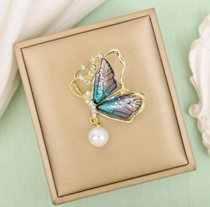 Broche papillon dorée élégante avec ailes dégradées bleues et perle blanche
