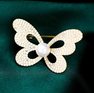 Élégante broche papillon dorée ornée de zircons et d'une perle sur velours vert foncé