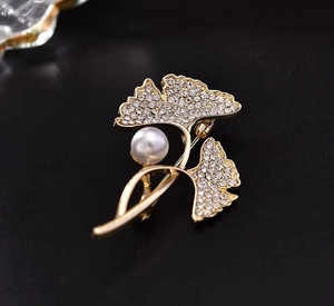 Macro shot of ginkgo leaf brooch with sparkling crystals and a white center pearl