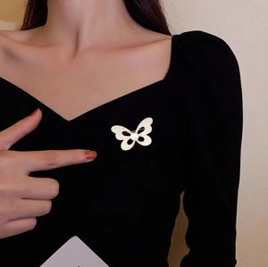 Détail d'une broche papillon étincelante avec perles sur une robe noire à col en v