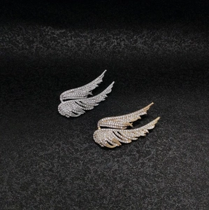 Elegant gold and silver wing brooches with micro-pave crystals on black background