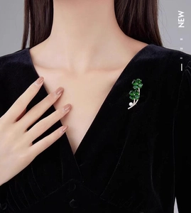 Detailed view of gold clover brooch with emerald zircon and pearl on black velvet