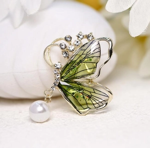 Broche papillon élégante aux ailes vertes avec perle sur fond de pierre blanche